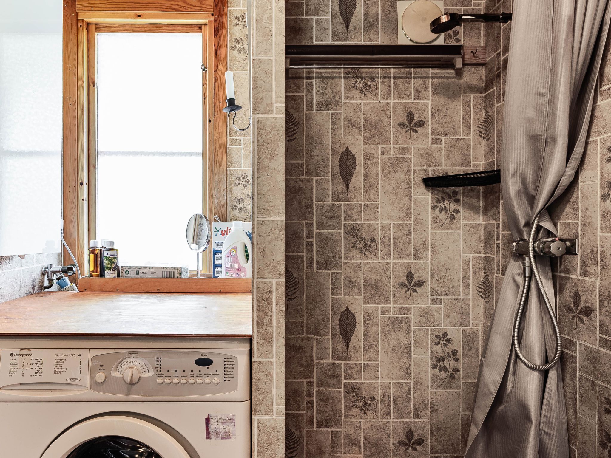 A laundry area with a washing machine, a mirror, and a window.