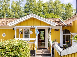 A yellow building with the number 40, a porch with potted plants, and a flag. - Kvarnfallet 40 by Interhome (Källsjö)