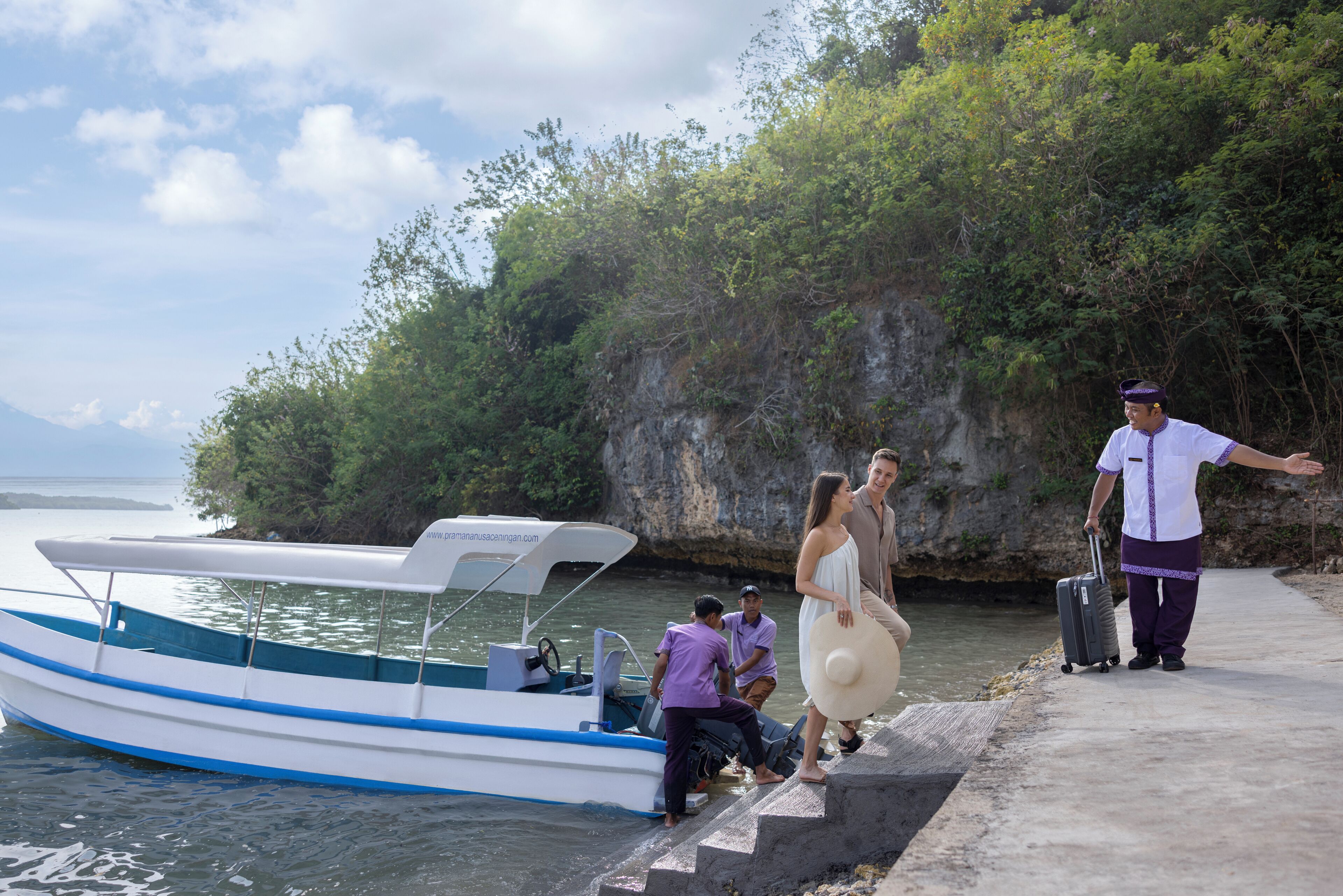 A boat docked at a pier with a rocky cliff in the background.