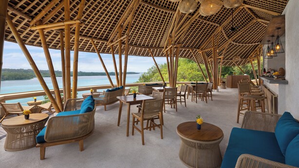 Een terras met rieten meubels, een bar en uitzicht op zee.