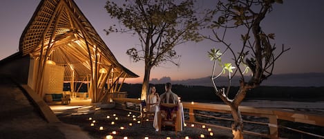 A romantic outdoor seating area with a wooden structure and a view of the water.