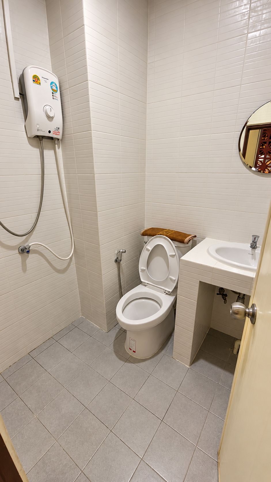 A small bathroom with a toilet, a shower unit, and a sink.