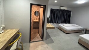 Ett kompakt hotellrum med ett skrivbord i trä, en säng med en vit madrass, ett litet badrum med en spegel och en luftkonditioneringsanläggning som är monterad i taket.