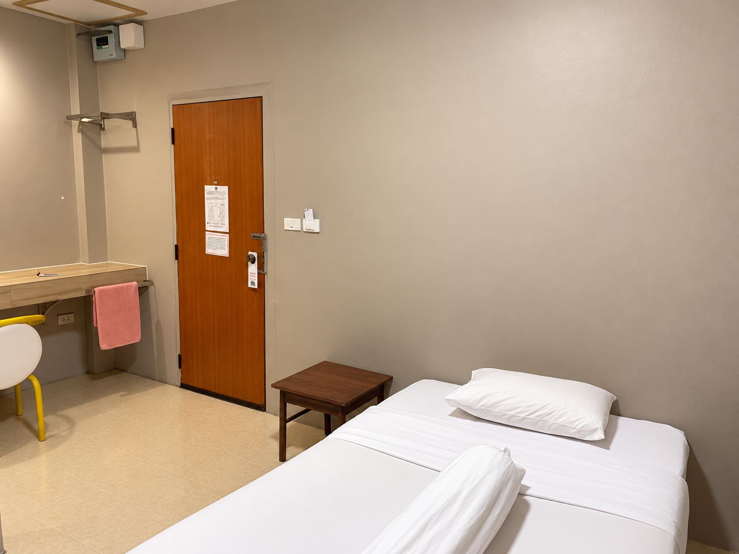 Una habitación de hotel con una cama, una mesita, un escritorio con silla y un baño.