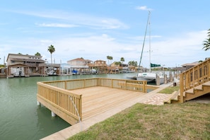 A marina with wooden docks, boats, and houses in the background. - Palacio Unit 2 (Port Isabel)