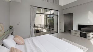 Ein modernes Schlafzimmer mit einem großen Bett, einem Fernseher und einer Schiebetür zu einem Balkon.
