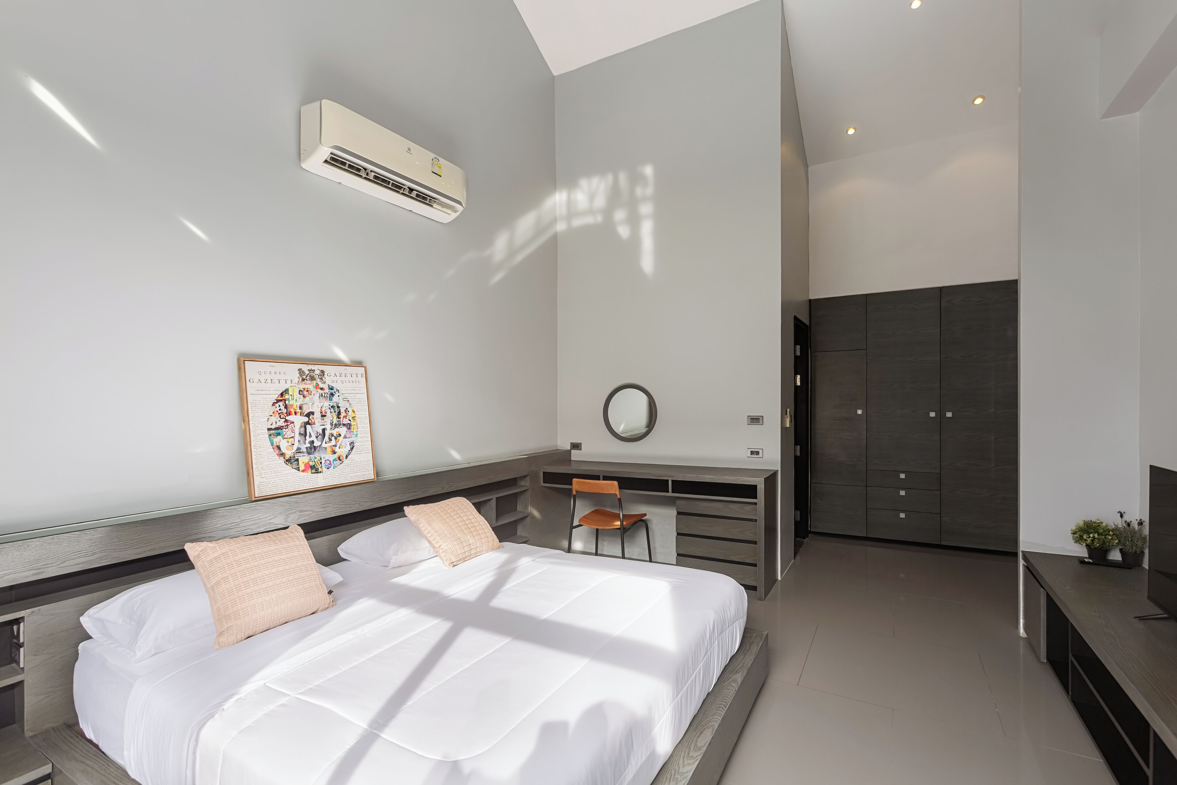 A modern bedroom with a large bed, a desk, and a wardrobe.