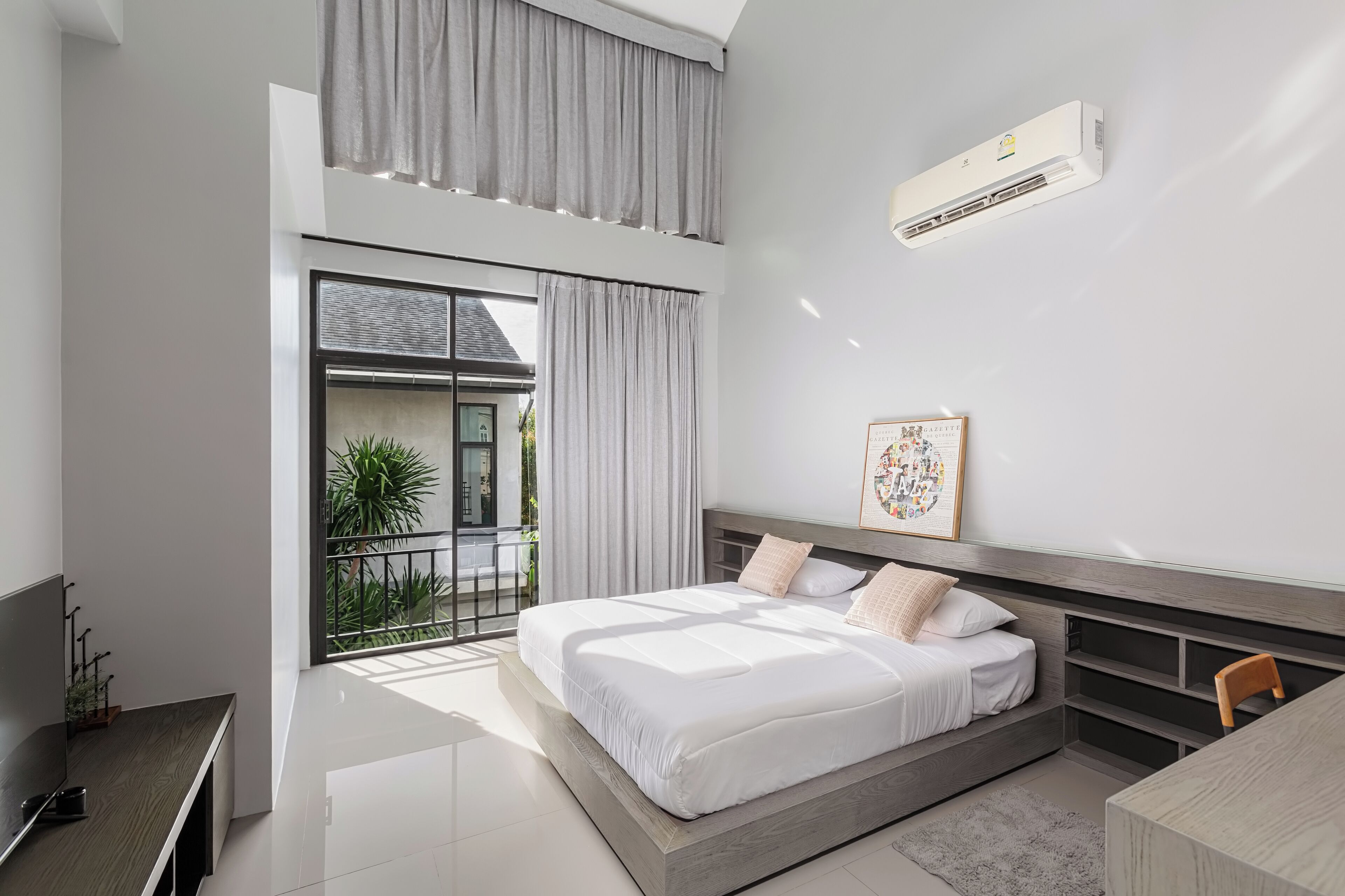 Quarto moderno com uma cama grande, televisão e varanda com cortinas.