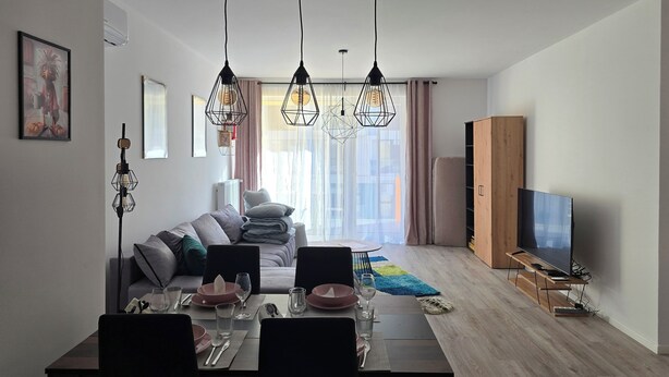 Un soggiorno moderno con zona pranzo, un divano, una TV e un mobile in legno.