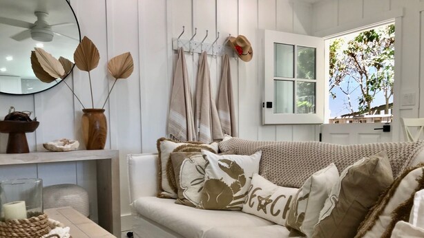 Un salon moderne avec un canapé blanc, des coussins décoratifs, une table basse en bois et un miroir au mur.