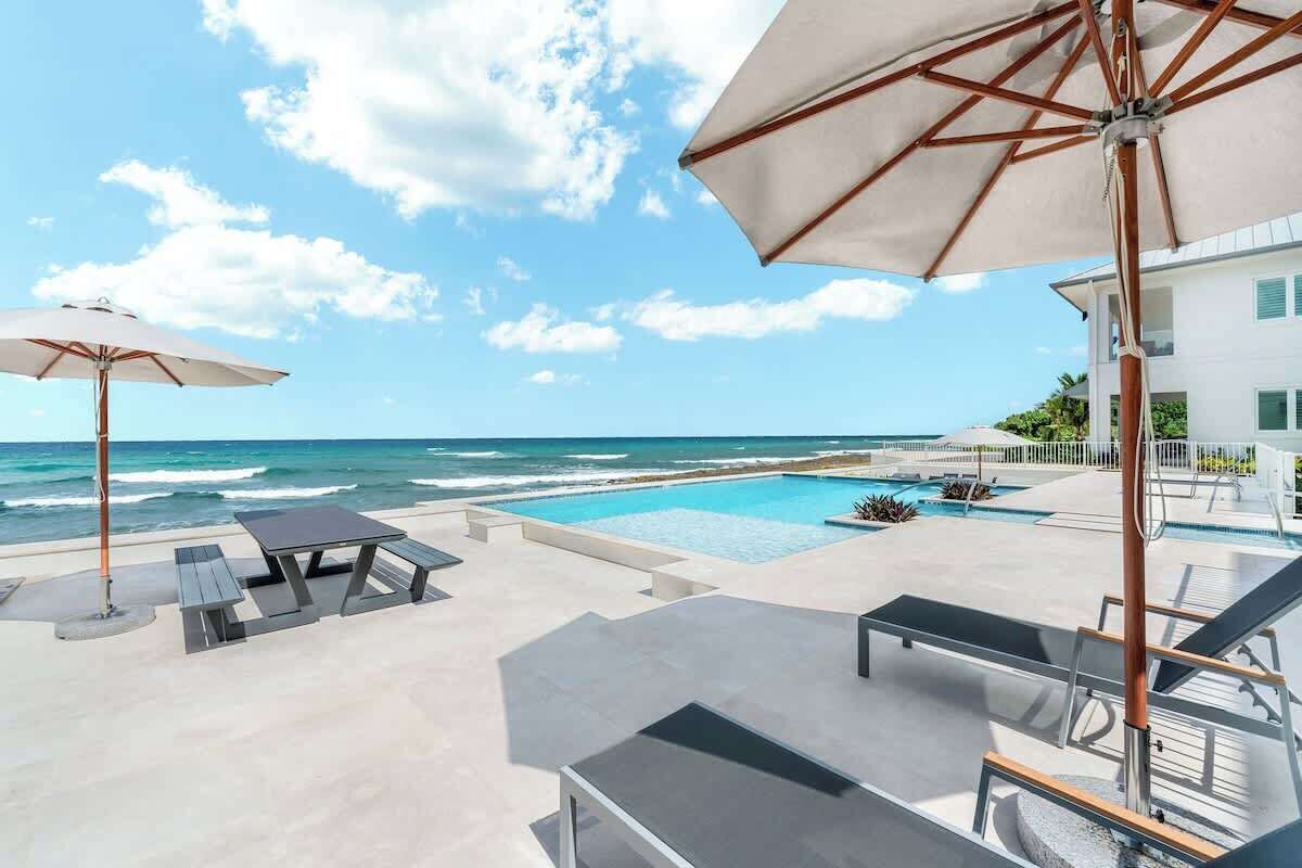A poolside area with lounge chairs, umbrellas, and a view of the ocean.