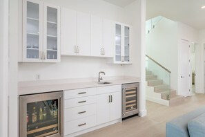 Una cocina moderna con armarios blancos, horno empotrado y refrigerador de acero inoxidable.