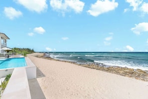 Ein Strandgrundstück mit Swimmingpool, Strand und Meerblick.