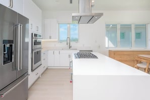 Une cuisine moderne dotée d’appareils électroménagers en acier inoxydable, de meubles blancs et d’un îlot central.