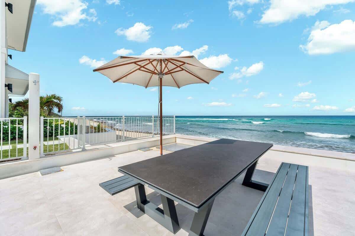 A terrace with a table and benches, overlooking the ocean.