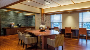 A spacious dining area with a large wooden table surrounded by chairs, a decorative vase, and a bar area with a coffee machine. - Palace Hotel KAKEGAWA (Kakegawa)