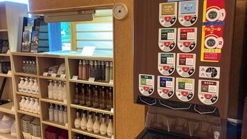 A vending machine with various drink options and a display of toiletries on shelves.