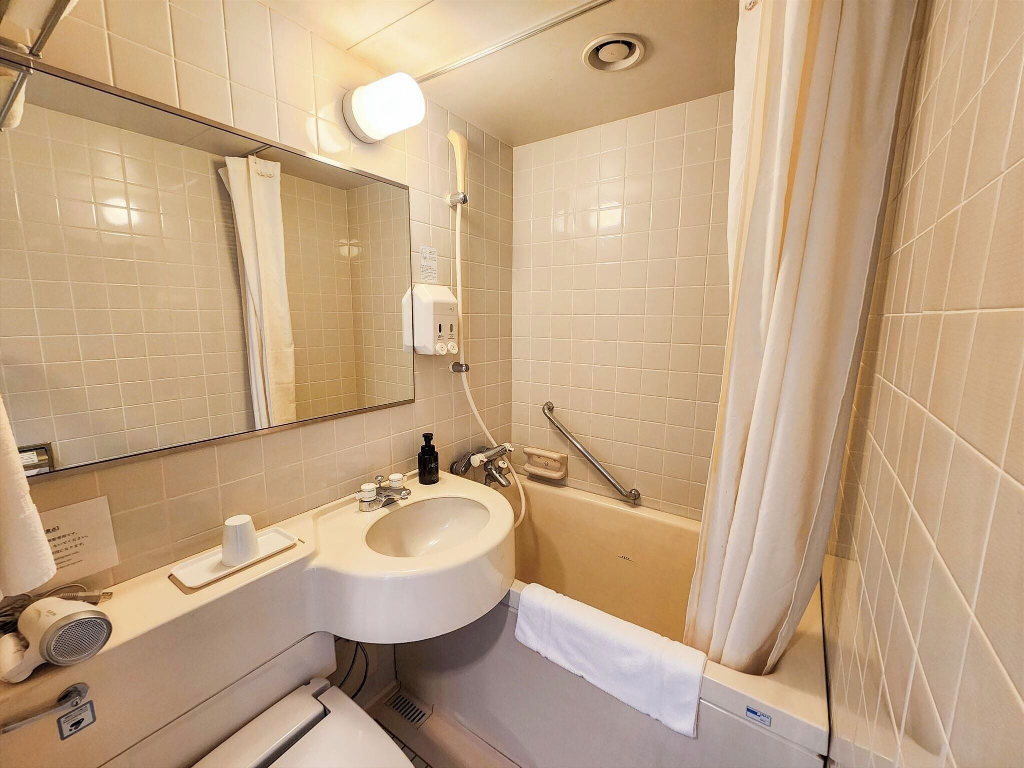 A bathroom with a sink, mirror, and bathtub.
