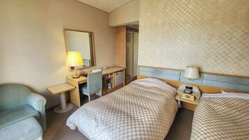 Une chambre d’hôtel avec deux lits, un bureau, une chaise, un miroir et une table de chevet avec une lampe.