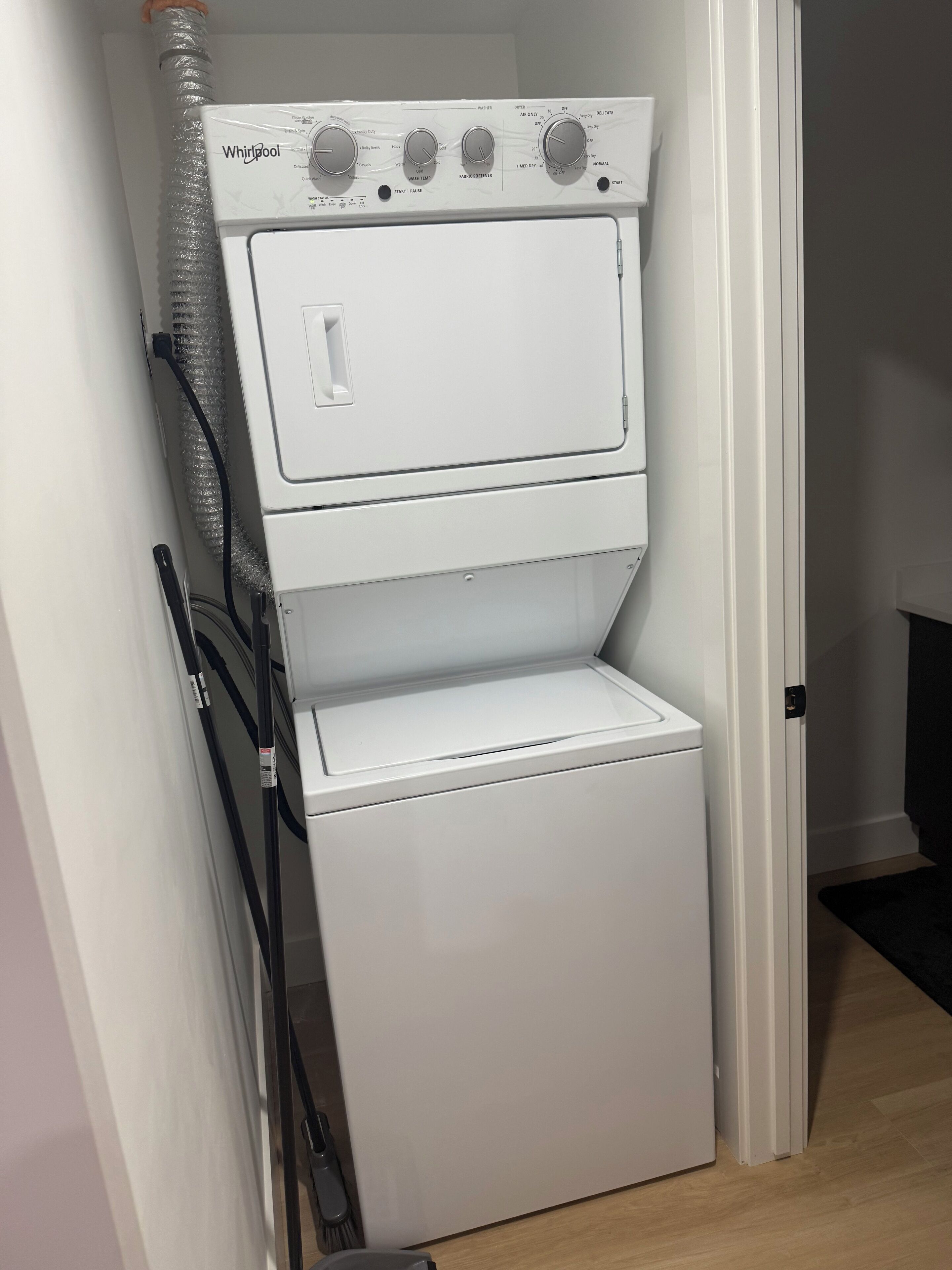 A Whirlpool stacked washer and dryer unit in a small laundry room.