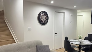 Ein modernes Wohnzimmer mit einem grauen Sofa, einem runden Couchtisch und einem Essbereich mit Tisch und Stühlen.