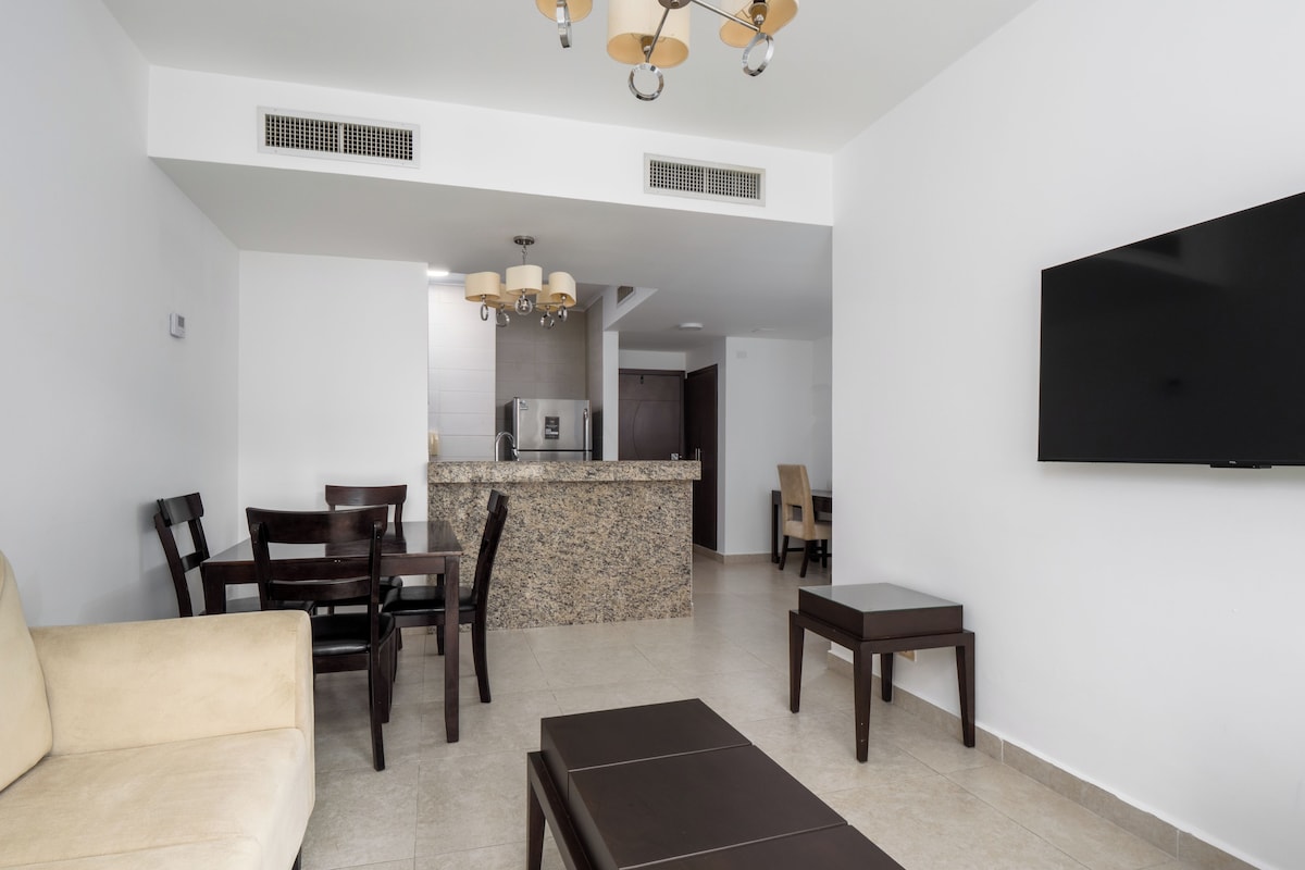 A modern living room with a sofa, a coffee table, and a TV mounted on the wall.