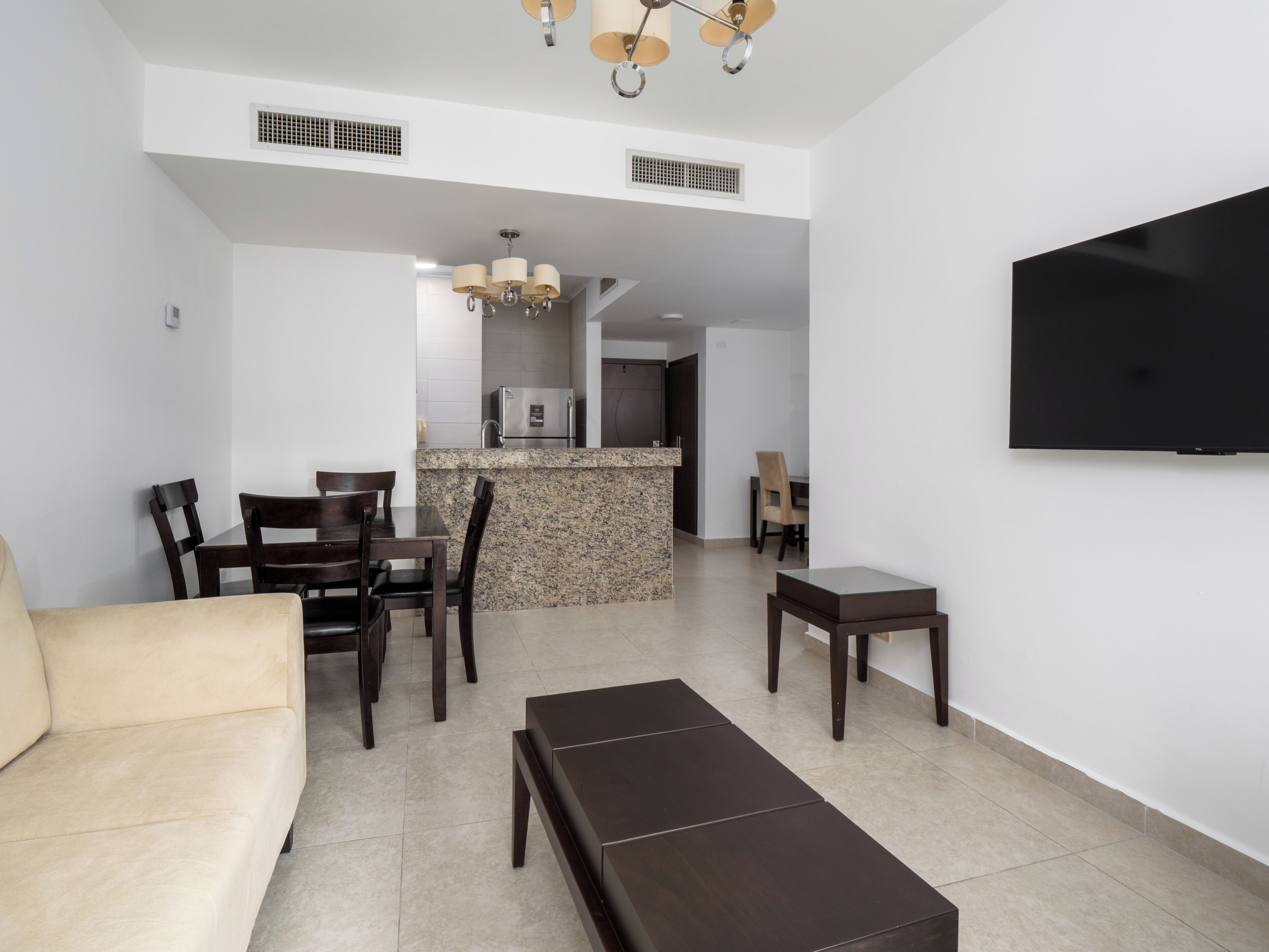 A modern living room with a sofa, a coffee table, and a TV mounted on the wall.