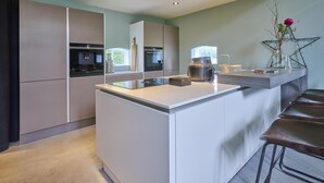 Una cocina moderna con una isla central, electrodomésticos integrados y una zona de bar con taburetes.