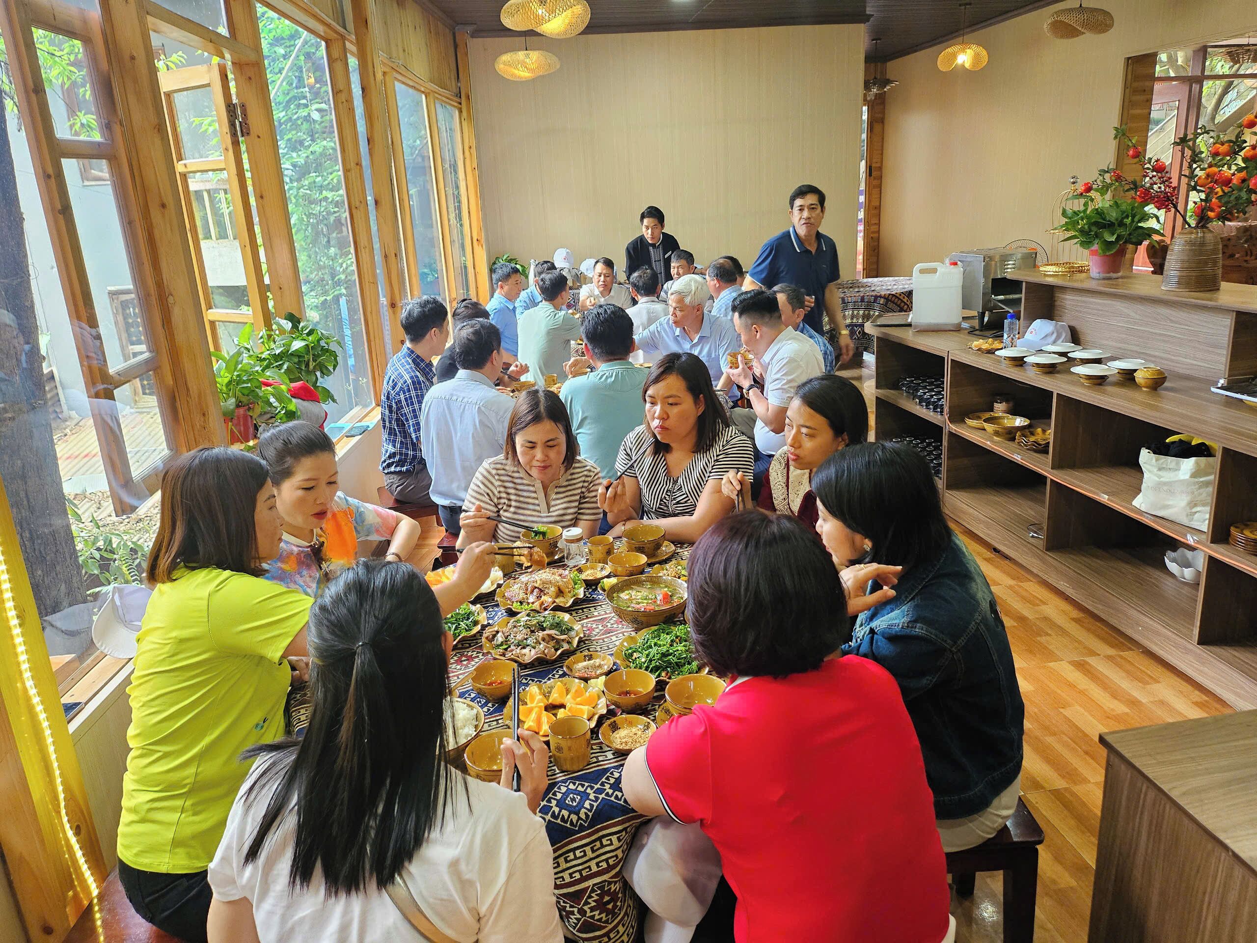 A communal dining area with wooden tables and chairs, surrounded by large windows.