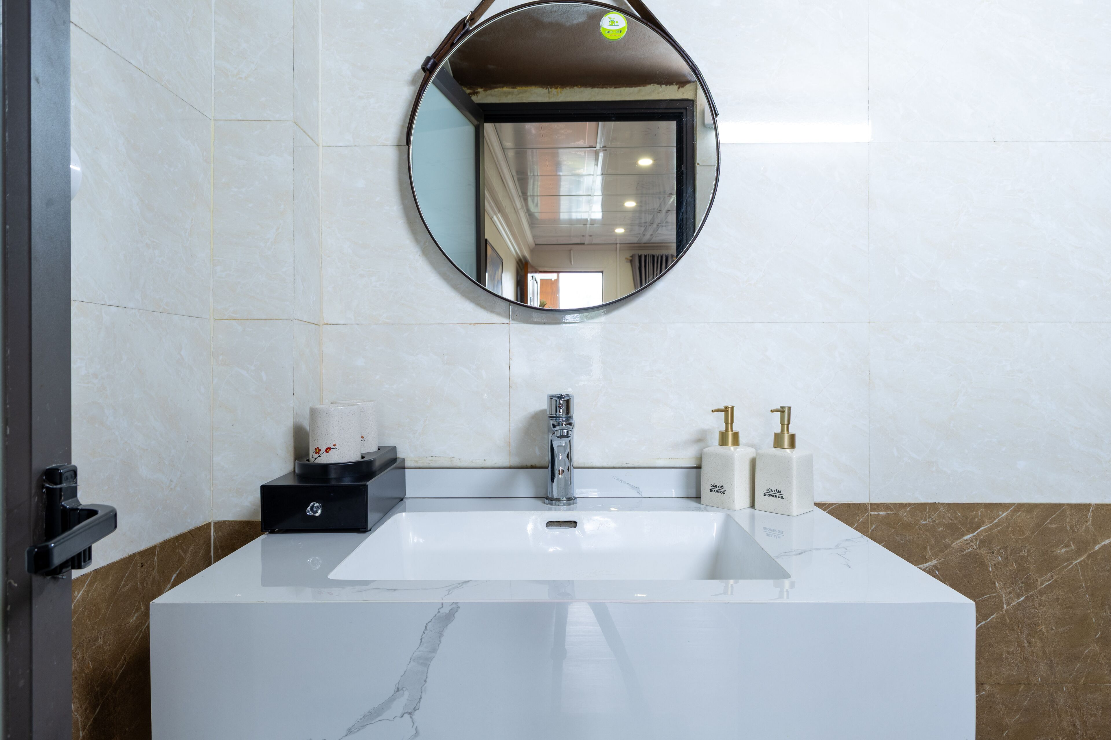 A bathroom with a white sink, a round mirror, and two bottles of shower oil.