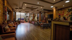 Um hall amplo com piso de madeira, um balcão de recepção e uma área de estar com sofás e cadeiras.