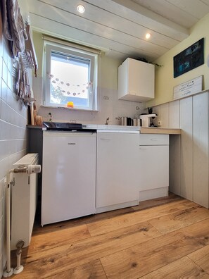 A compact kitchen with a built-in dishwasher, a window with a view, and a wooden floor.