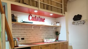 A kitchen with a 'Cuisine' sign, wooden cabinets, a black refrigerator, and a brick wall. - Small apartment in the center of Rome (Roma)