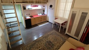 A compact kitchen with a 'Cuisine' sign, a dining table, a sofa, and a staircase. - Small apartment in the center of Rome (Roma)