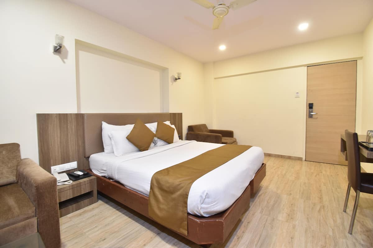 A hotel room with a bed, a desk, a chair, a wardrobe, and a ceiling fan.