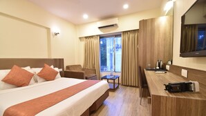 A hotel room with a large bed, a desk, a chair, and a TV. - Hotel Atlantic (Mumbai)