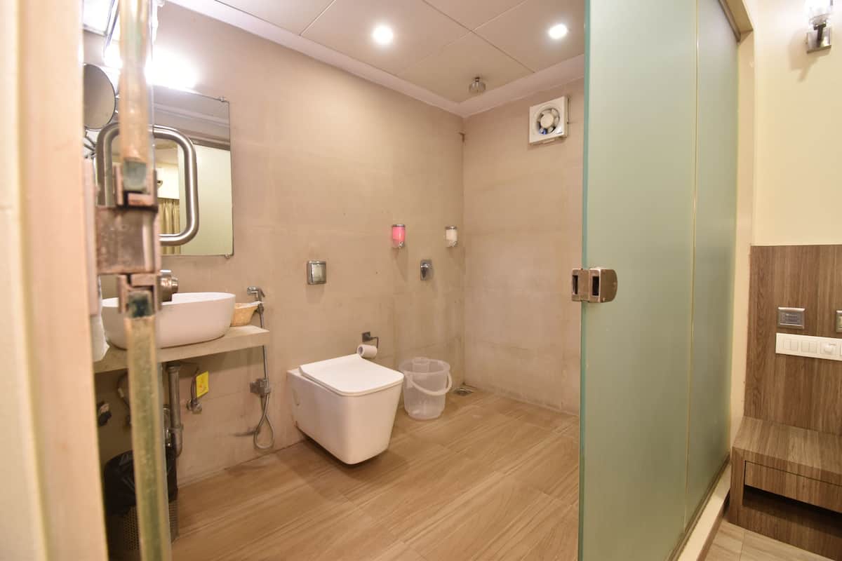A bathroom with a toilet, sink, mirror, and shower area.