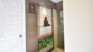 A reception area with a Buddha statue on a glass shelf, a prayer plaque, and a fish tank. - Hotel Atlantic (Mumbai)