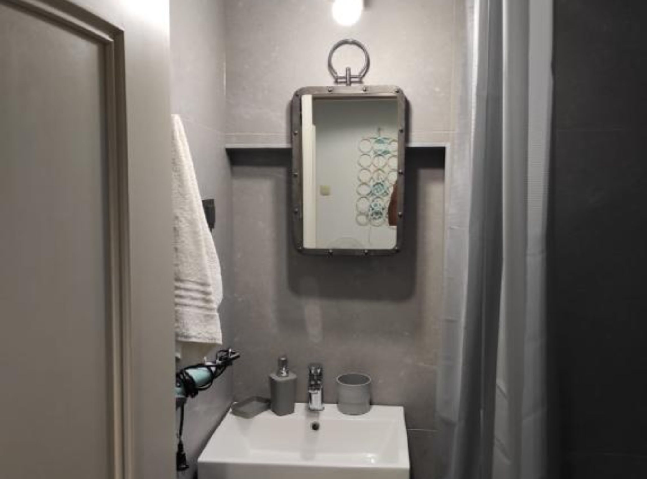 Ein Badezimmer mit Waschbecken, Toilettenpapier und einem Handtuch, das an der Wand hängt.