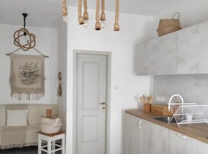 A kitchen with a wooden countertop, hanging light fixtures, a white door, and a woven basket on the wall. - Modern Beachfront Apartments Near Šibenik (Vodice)
