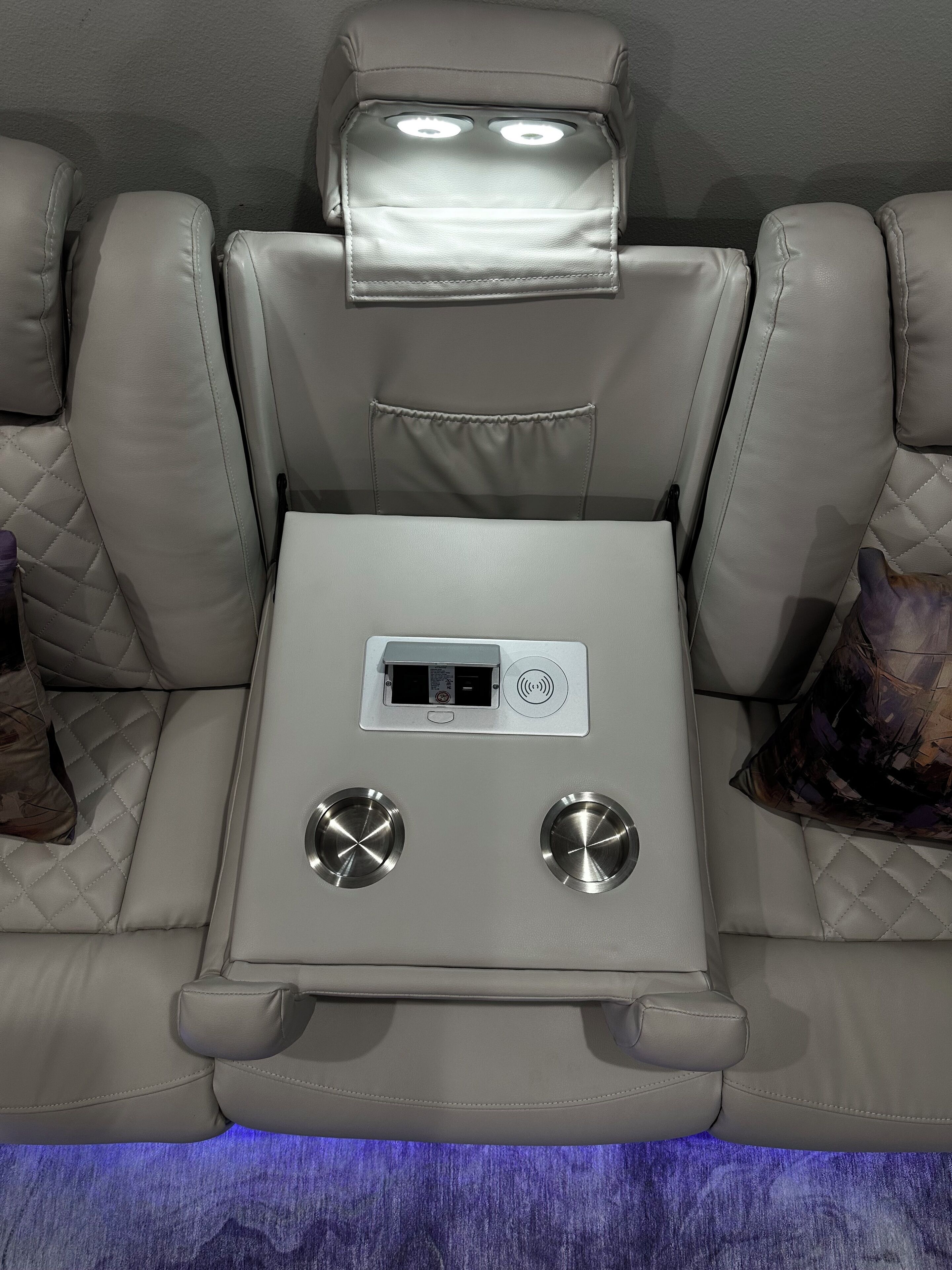 A reclining seat with a control panel, cup holders, and a footrest.