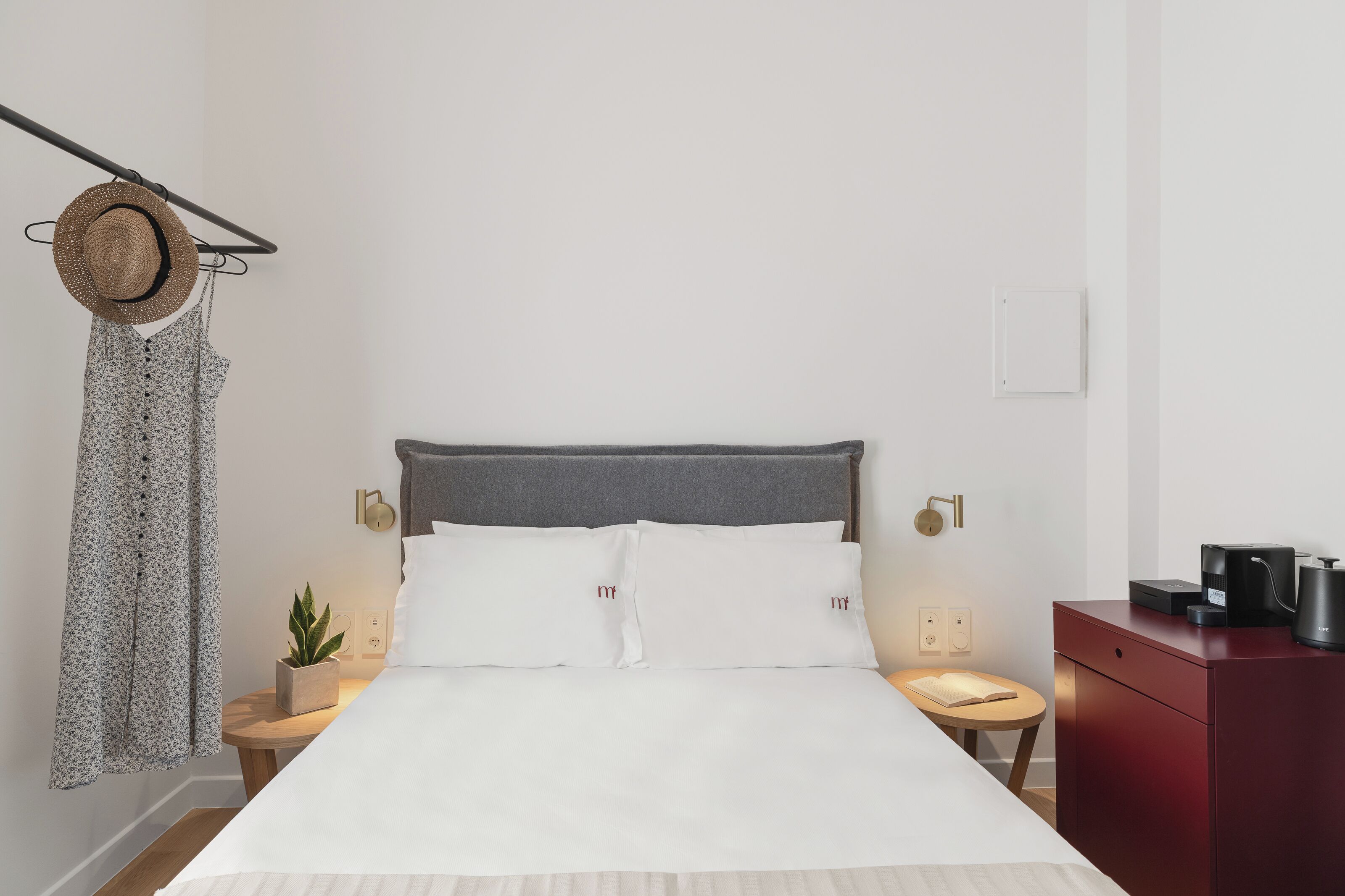 A neatly made bed with white linens, a grey headboard, and two bedside tables with lamps.