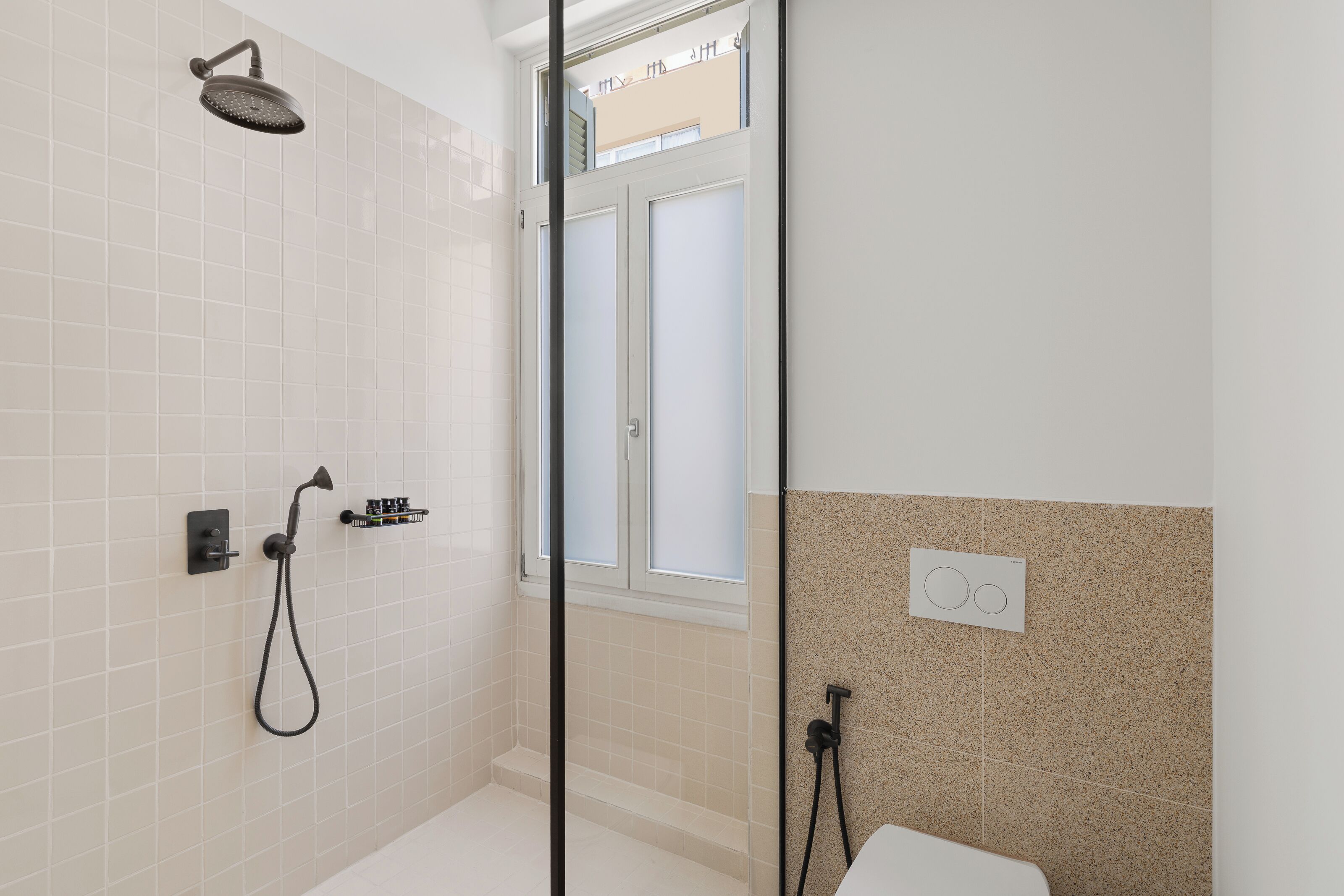 A modern bathroom with a shower, toilet, and a window.