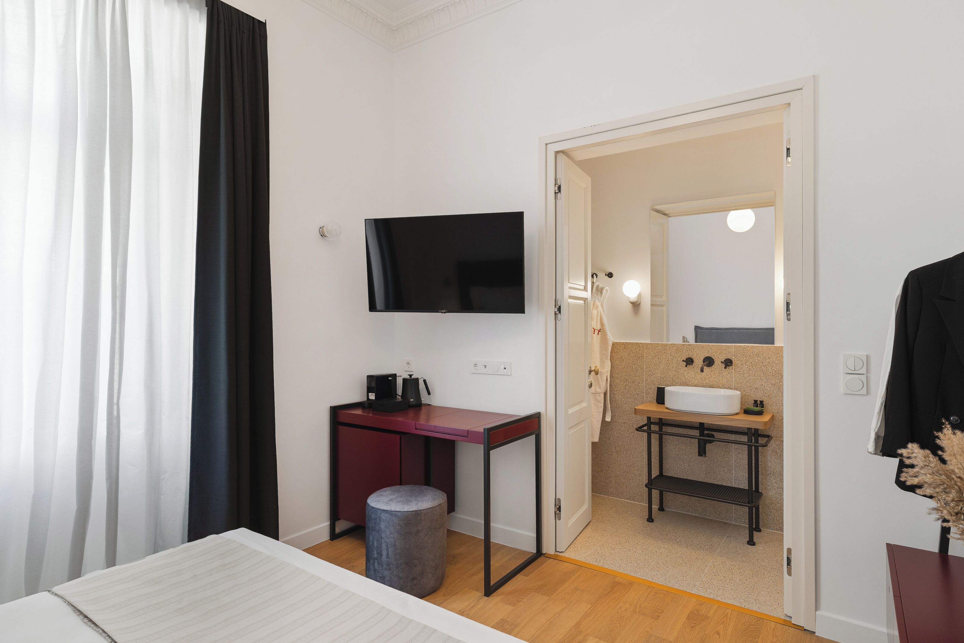 Camera d'albergo con un letto, una scrivania con televisore, un piccolo lavandino e uno specchio.