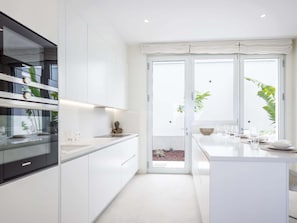 A modern kitchen with white cabinetry, a built-in oven, and a large window with a view of greenery. - Luxury Villa Martina private heated pool, jacuzzi Abama (Guía de Isora)