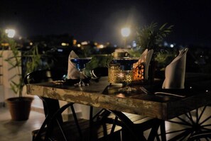 A table set outdoors at night with a lantern, glasses, and a bottle. - janak vilas (Udaipur)