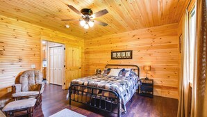 A wooden cabin bedroom with a bed, chair, and a ceiling fan. - 18 Mi to Red River Gorge: Beattyville Retreat (Beattyville)