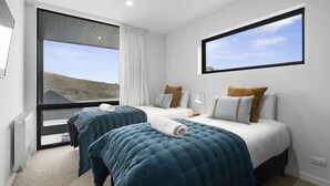 Ein Hotelzimmer mit zwei Betten, einem großen Fenster und Blick ins Freie.
