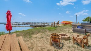 A beachside setting with a wooden deck, a red umbrella, and a view of the water and dock. - Resort Condo w/ Marina Access in Williamsburg! (Williamsburg)