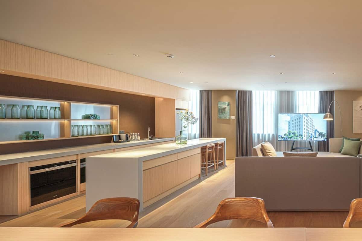 Une chambre d’hôtel moderne dotée d’un coin cuisine, d’un canapé, d’une table à manger avec des chaises et d’un grand lit.